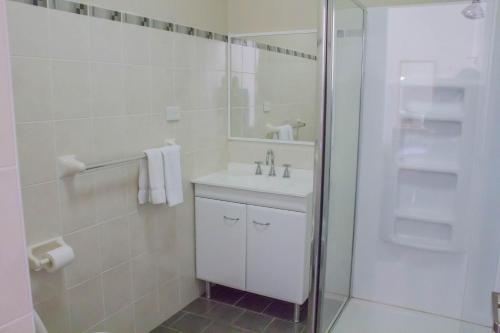 a white bathroom with a sink and a shower at Gardners Inn Hotel in Blackheath