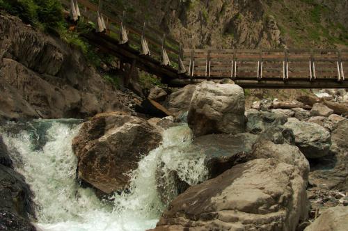 a bridge over a river with water rushing over rocks at Haus Fischer in Pettneu am Arlberg