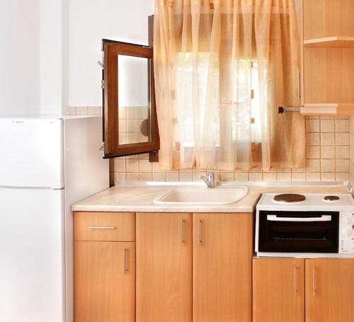 a small kitchen with a sink and a stove at Katerina-Maria Studios & Apartments in Vourvourou