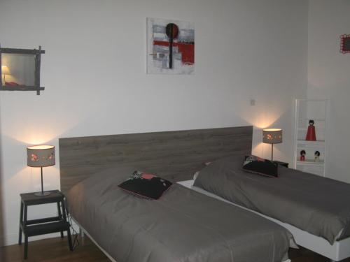two beds in a room with two lamps on them at Les Jardins du Golf in Metz