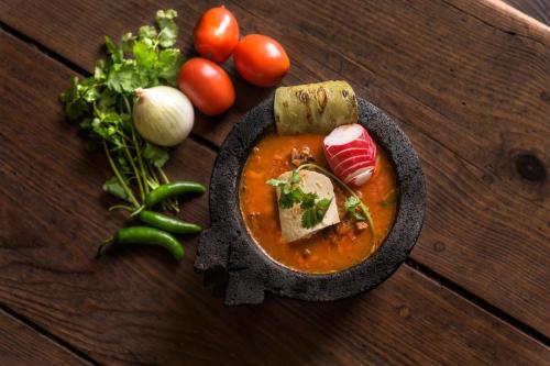 a bowl of soup with meat and vegetables on a wooden table at Tapalpa Country Club Hotel in Tapalpa