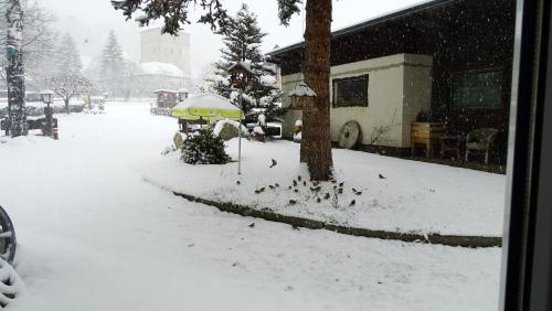 a snow covered street with a tree and an umbrella at Ferienhaus-Römerthurm in Schöder