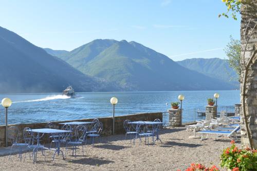 a group of tables and chairs next to a body of water at Villa Belvedere Como Lake Relais in Argegno