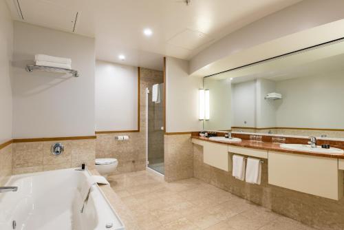 a bathroom with a tub and two sinks and a toilet at Distinction Christchurch Hotel in Christchurch