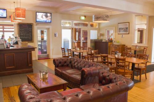 a restaurant with leather couches and tables and a bar at Gardners Inn Hotel in Blackheath