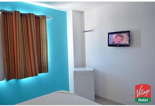にあるVillage Hotel Belémの壁にテレビとベッドが備わる客室です。
