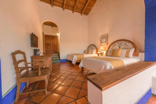 a bedroom with two beds and a table and a chair at Tapalpa Country Club Hotel in Tapalpa