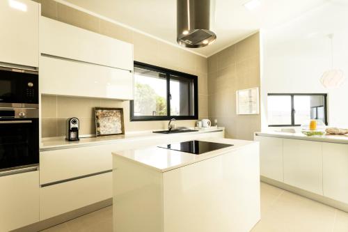 a white kitchen with white cabinets and a sink at Casa Tazmin in Santo Isidoro