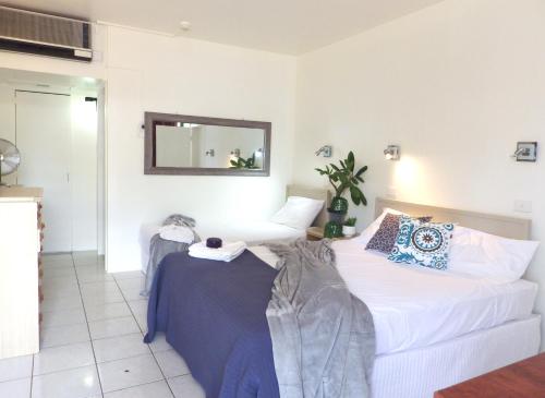 a bedroom with two beds and a mirror at Darwin Poinciana Inn in Darwin
