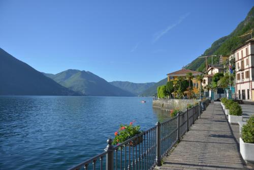 a walkway next to a lake with houses and mountains at Villa Belvedere Como Lake Relais in Argegno