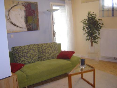 a living room with a green couch and a table at ApartmentHotel Vollumen in Redwitz an der Rodach