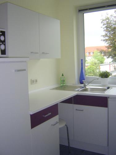 a kitchen with white cabinets and a sink and a window at ApartmentHotel Vollumen in Redwitz an der Rodach