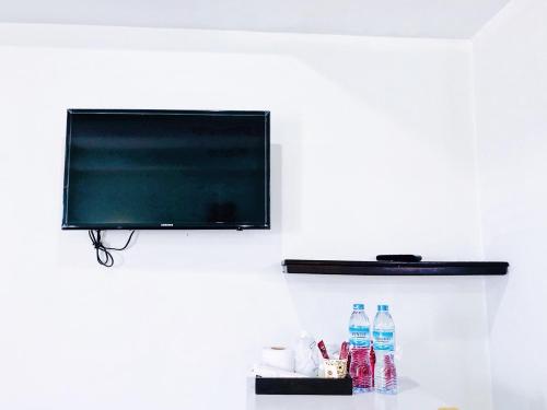 J Jamroon Place في ناخون راتشاسيما: تلفزيون بشاشة مسطحة معلق على جدار مع زجاجات مياه