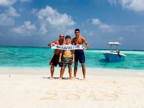 a group of people standing on a beach with a surfboard at Mathiveri Thundi Inn in Mathiveri