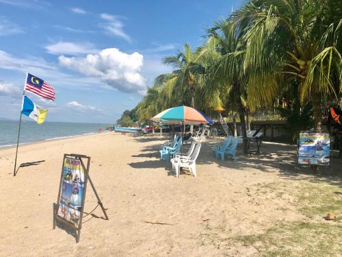 a beach with chairs and an umbrella and a flag at G Beach Front Villa in Batu Ferringhi