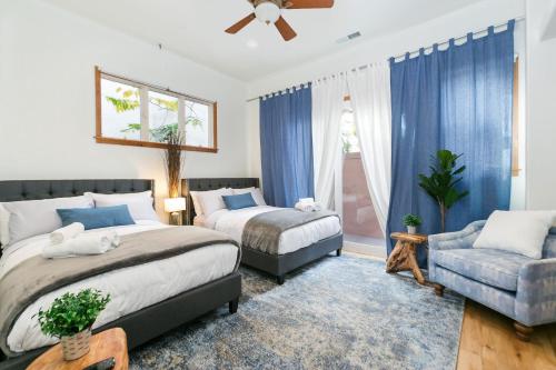 two beds in a bedroom with blue curtains and a couch at Culver city ·4045 Jackson in Los Angeles