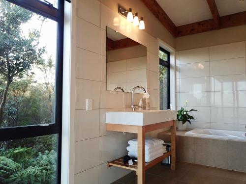 uma casa de banho com um lavatório, uma banheira e um espelho. em Te Kahu em Whangarei