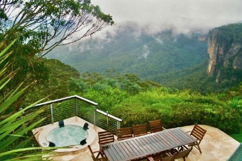 a hot tub and chairs with a view of the mountains at Amaroo Mountaintop Villa in Katoomba