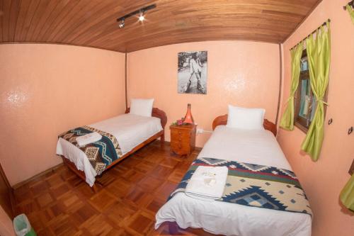 two beds in a small room with wooden floors at La Casa del Molino Blanco B&B in Baños