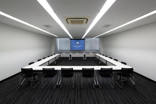 a conference room with a screen and chairs in it at HOTEL MYSTAYS Shin Osaka Conference Center in Osaka