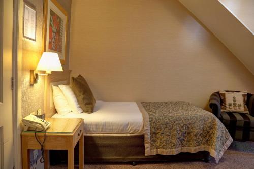 a bedroom with a bed and a table with a phone at Norfolk Royale Hotel in Bournemouth
