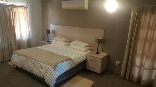 a bedroom with a bed and a lamp on a night stand at 12 On Vaal Drive Guesthouse in Vanderbijlpark