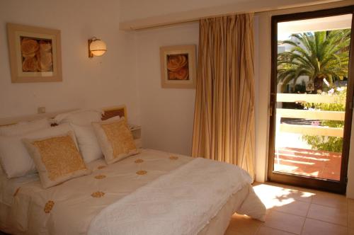 a bedroom with a bed and a large window at Capitalmoura Mouragolf Village in Vilamoura