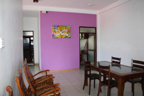 a dining room with a purple wall and a table and chairs at Saga Home in Ambalangoda