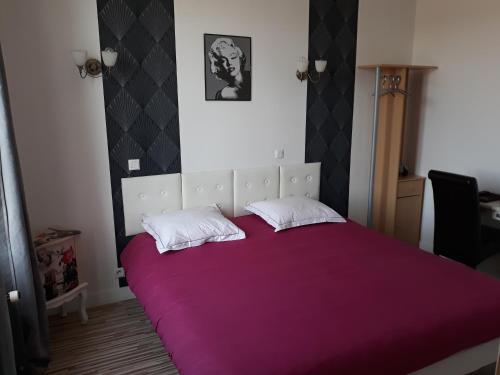 a bedroom with a large purple bed with two pillows at Hotel De La Gare in Sainte-Gauburge-Sainte-Colombe
