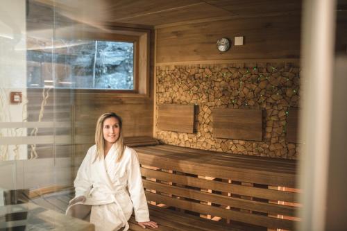 a woman is sitting in a sauna at Das Salvator Iris Porsche Landhotel in Friesach