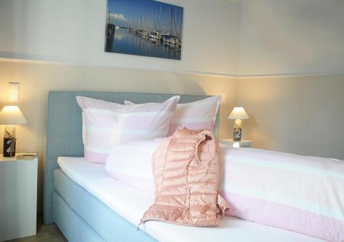 a bedroom with a bed with white and pink pillows at Ferienwohnung KNUT am Hafen in Heiligenhafen