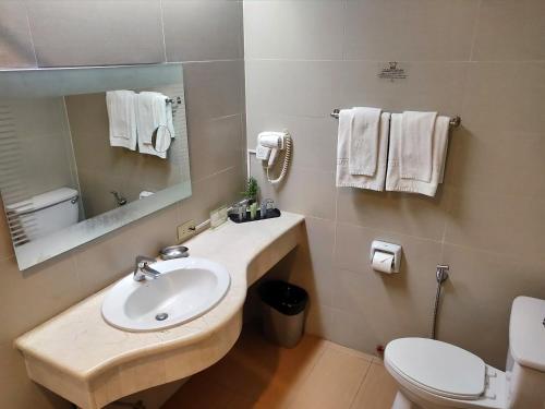 a bathroom with a sink and a toilet and a mirror at Hotel Kimberly Manila in Manila