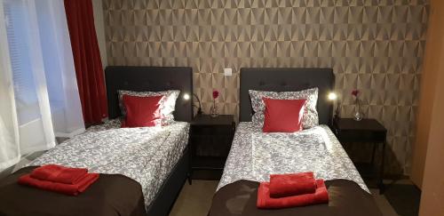 two beds in a room with red pillows on them at Pension STELLA in Lutherstadt Eisleben
