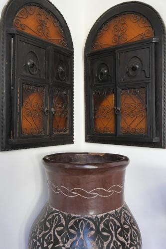 a vase sitting in front of two windows at Riad Terra Bahia in Marrakech