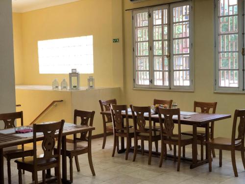 a dining room with tables and chairs and windows at Hospedaria Vianense in Luanda