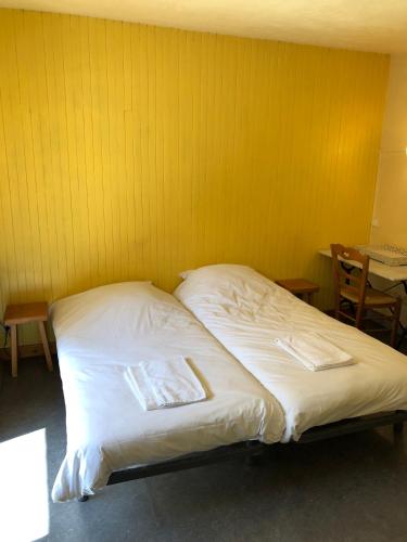 - une chambre avec 2 lits et un mur jaune dans l'établissement Royal 513, à Brides-les-Bains