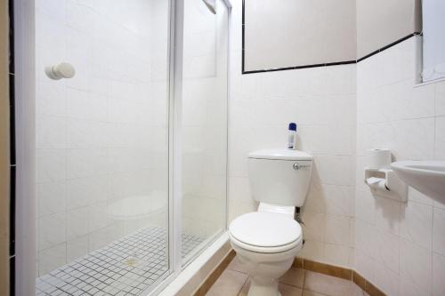 a white bathroom with a toilet and a shower at The Reef Apartments in East London