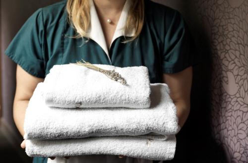 a woman holding a stack of towels and a feather at Acropolis Hill Hotel in Athens