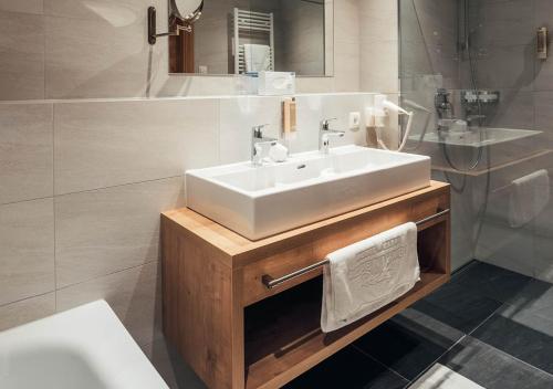 La salle de bains est pourvue d'un lavabo blanc et d'une baignoire. dans l'établissement Hotel Garni Alpenjuwel Residenz, à Serfaus