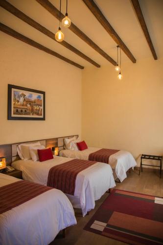 a hotel room with three beds with red pillows at La Casona Monsante in Chachapoyas