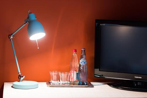 a desk with a lamp and a television and drinks at Le Central Boutique Hôtel in Beaune