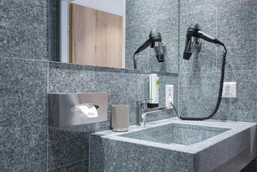 a bathroom with a sink with a shower and a mirror at Hotel Vaduzerhof by b-smart in Vaduz