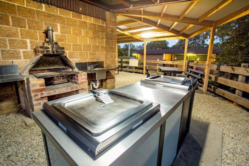 a outdoor kitchen with a grill and a table with a stove at Castlemaine Gardens Luxury Glamping in Castlemaine