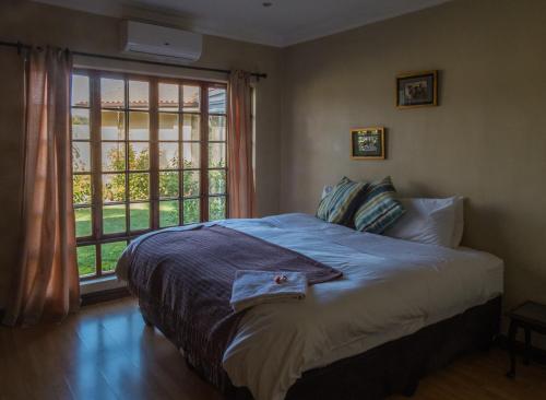 a bedroom with a bed and a large window at Ekhaya Guest House in Ballito