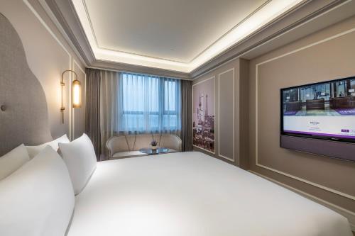a hotel room with a large bed and a flat screen tv at Mercure Shanghai Hongqiao Central in Shanghai