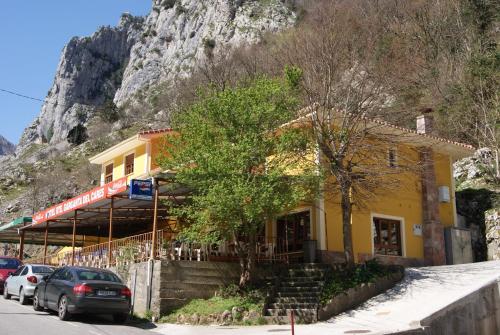 un edificio amarillo con coches estacionados frente a él en Hotel Garganta del Cares, en Poncebos