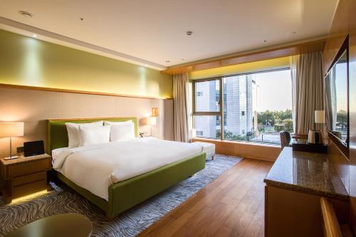 a hotel room with a bed and a large window at Baymond Hotel in Busan