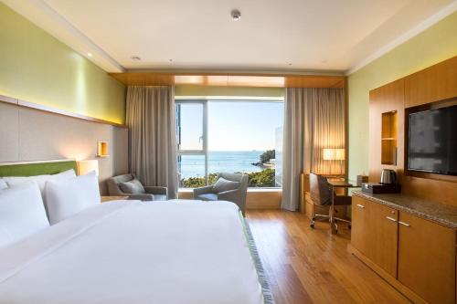 a hotel room with a bed and a large window at Baymond Hotel in Busan