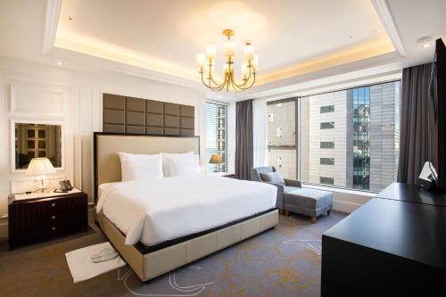 Un dormitorio con una gran cama blanca y una lámpara de araña. en Baymond Hotel en Busan
