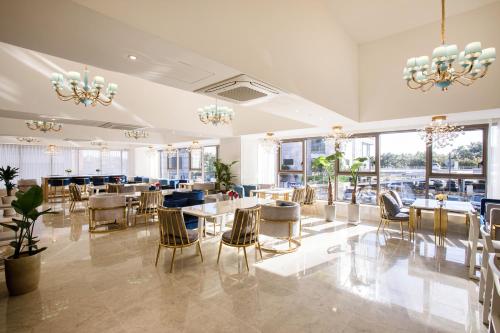 a dining room with tables and chairs and windows at Baymond Hotel in Busan